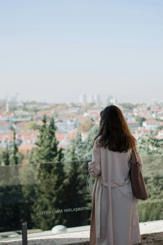 woman with long hair looking at city and tree line from hill