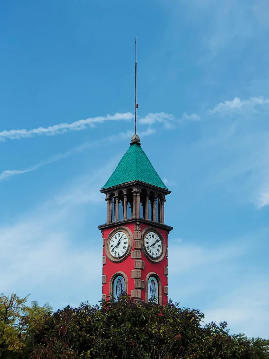 a small red clock tower with two clocks on each of it's sides