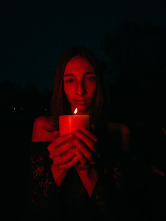 a woman holding up a candle at night