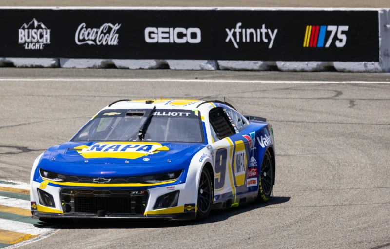 a race car on a race track with the sign coca cola behind it