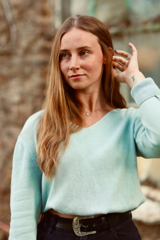 a woman with long hair holding her hand near her ear