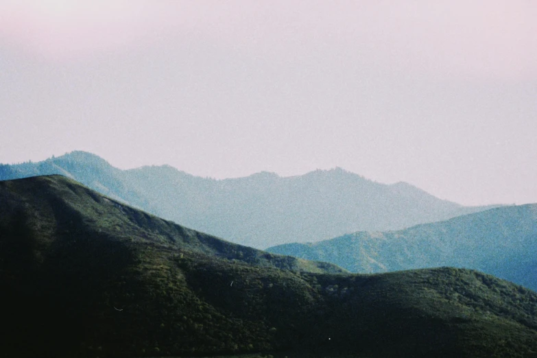 the hills and valleys surrounding a city are covered in green