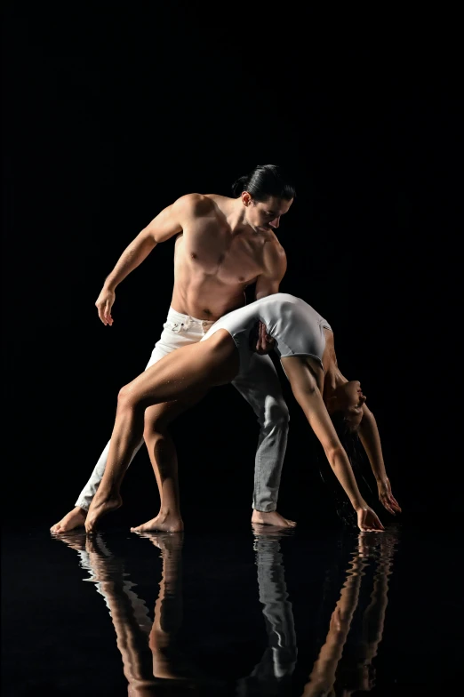 two dancers in the dark are practicing acrobatics