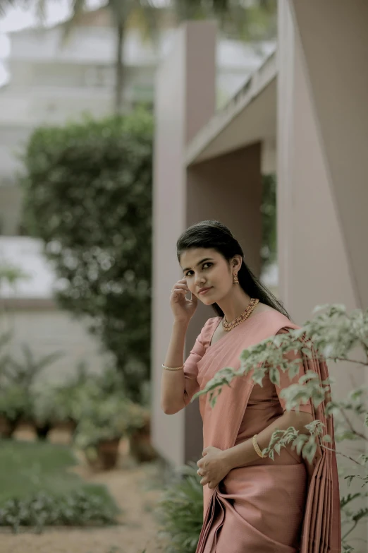 a woman is standing outside wearing a pink saree