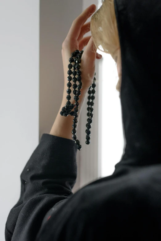 a woman with rosary beads looks at her reflection