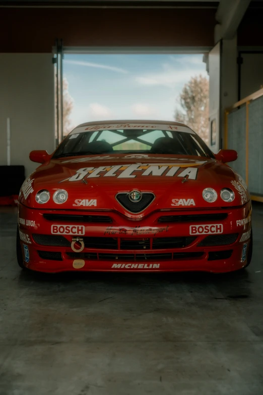 the front of a red sports car, with a painted logo on it