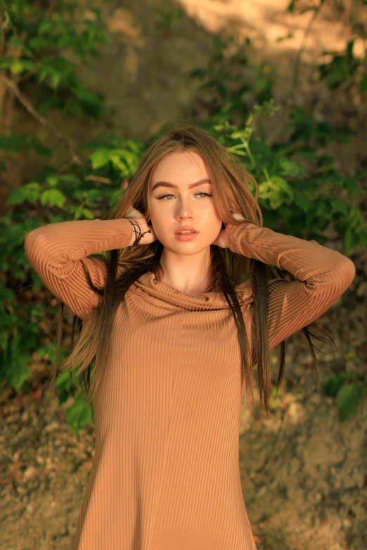 a woman posing on a path in a dress and holding her hair in one side