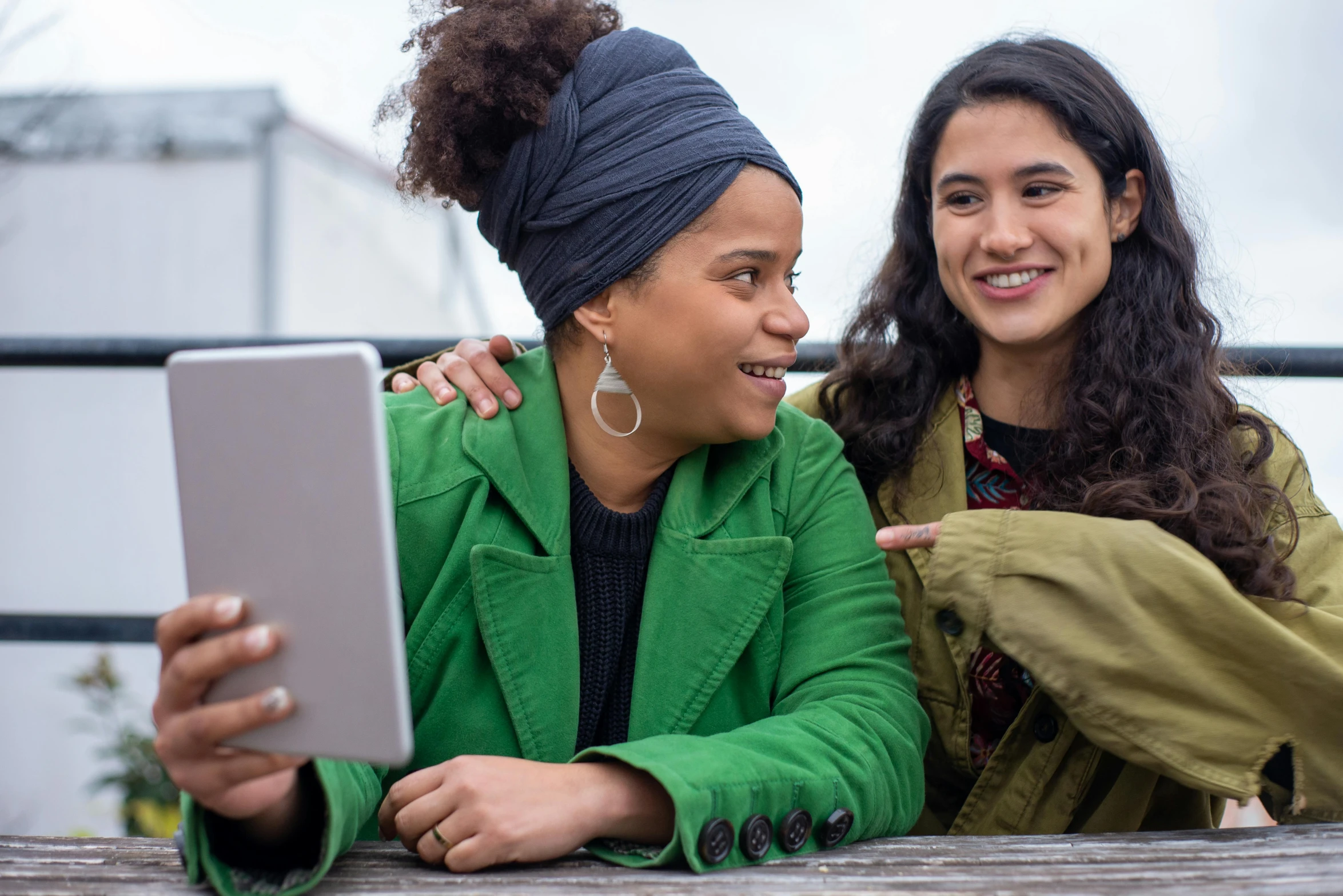 two women are sitting outside smiling at one another