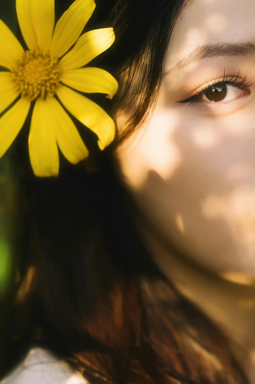 the sun shines on a woman's face with a single yellow flower on her hair