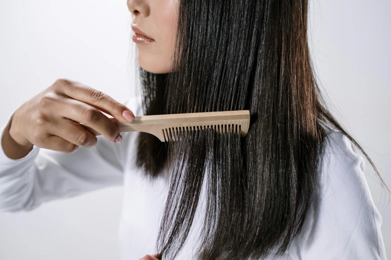 a person brushes their hair with a wood brush