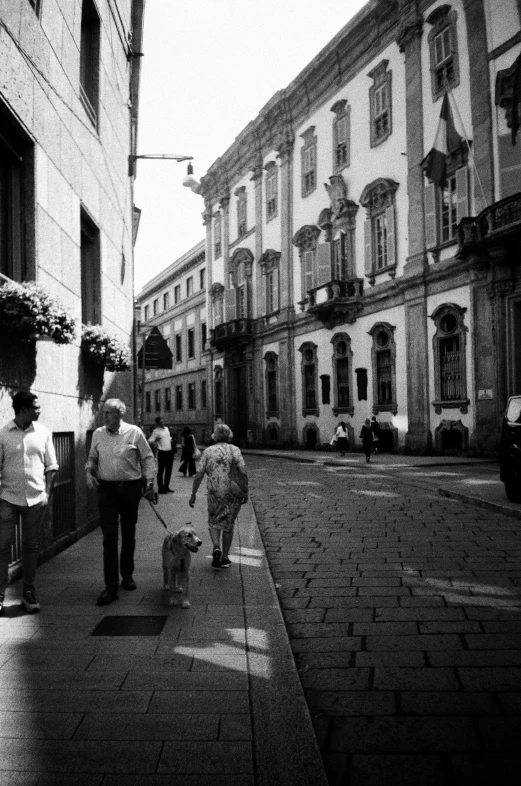 people walking down a brick sidewalk near tall buildings