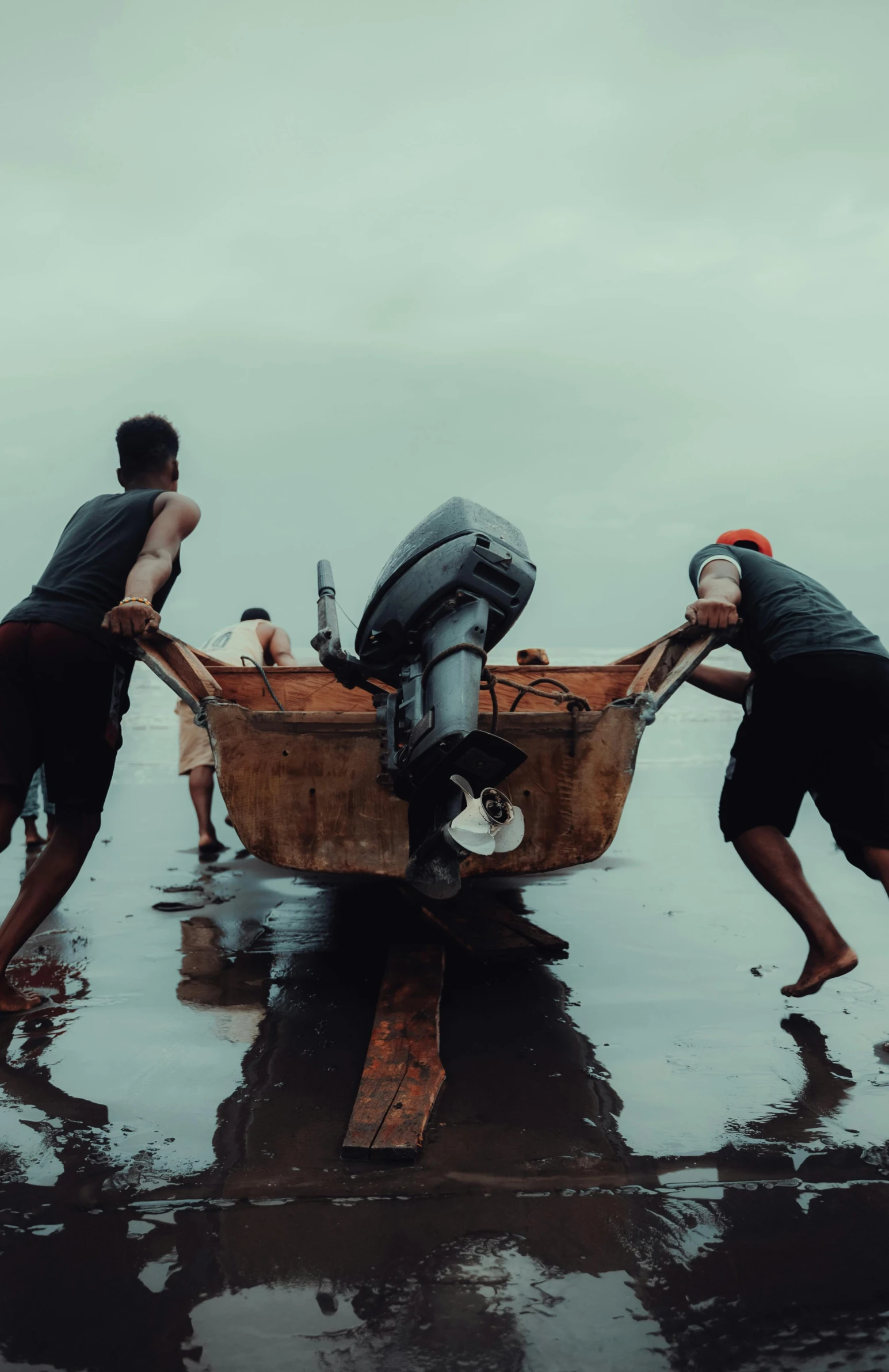 three men hing a boat on the wet beach