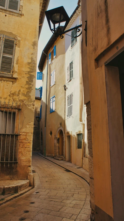 a narrow street has a lamp and old buildings