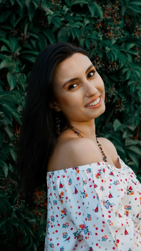 a woman wearing a white and blue shirt smiles at the camera