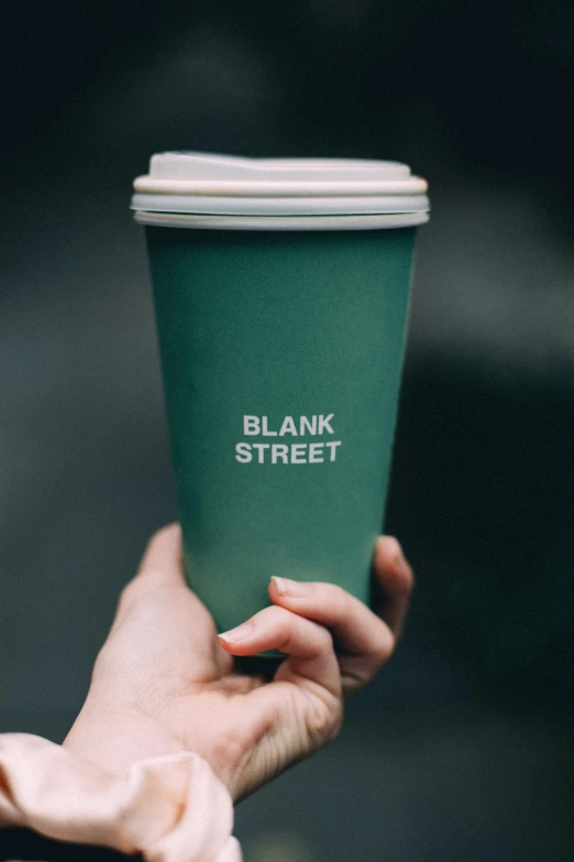 a woman holding up a cup of coffee with the text bank street on it