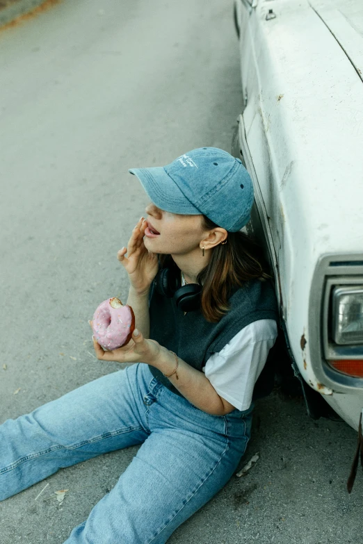 a girl laying on the side of the road while eating a donut