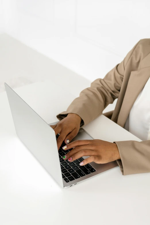 someone uses a lap top that is on top of a white table