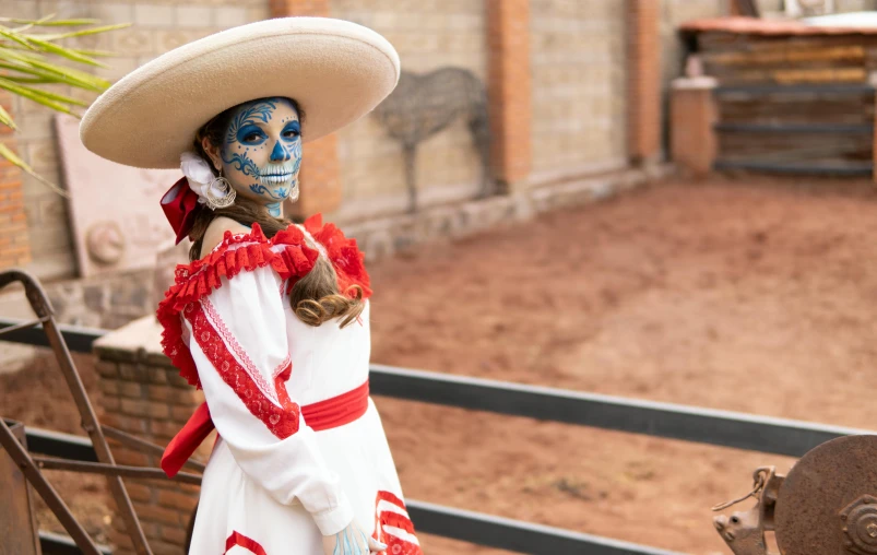 a mexican woman with face paint on standing in front of an iron gate