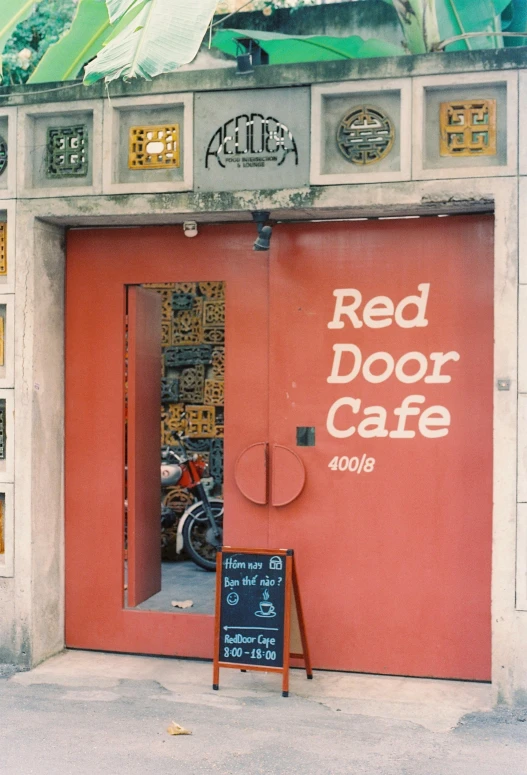 red door cafe on a city sidewalk is pictured in a vintage pograph