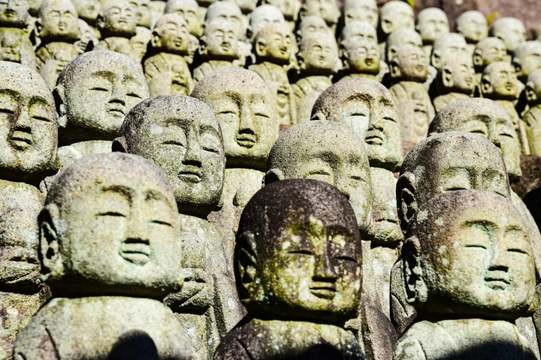 large array of heads of buddha statues in a wall