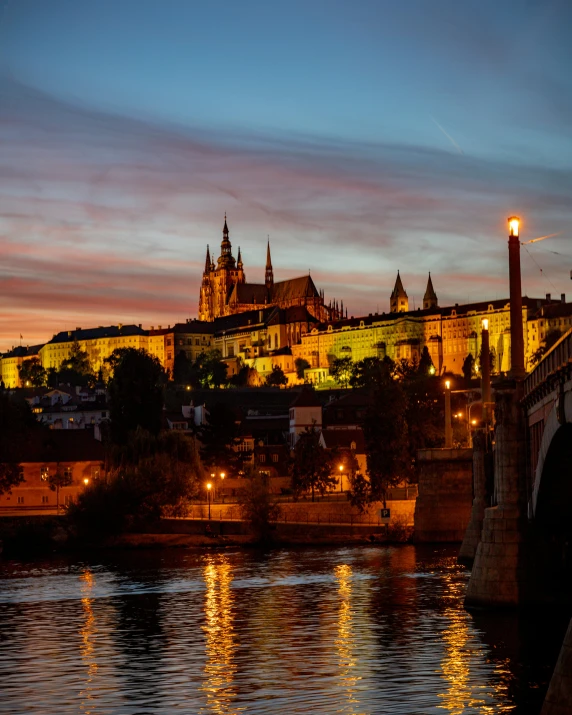 the castle lite up at dusk by the river