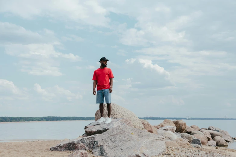 a man standing on a large rock in front of the ocean