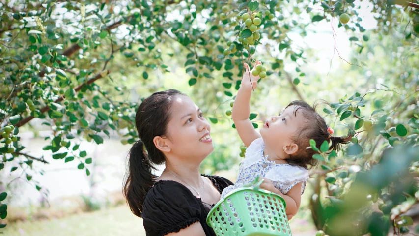 an adult and a young child in the grass under a tree