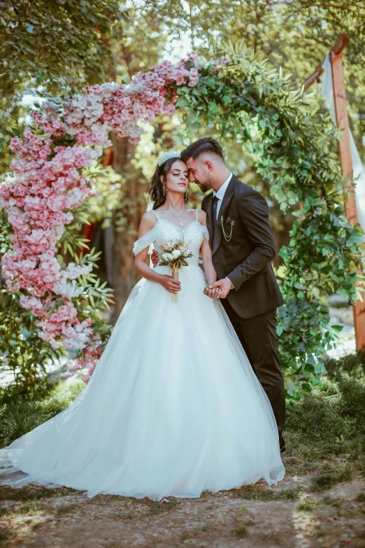 a newlywed couple standing under a wooden arch