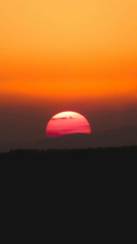 the sun sets in the sky over the countryside