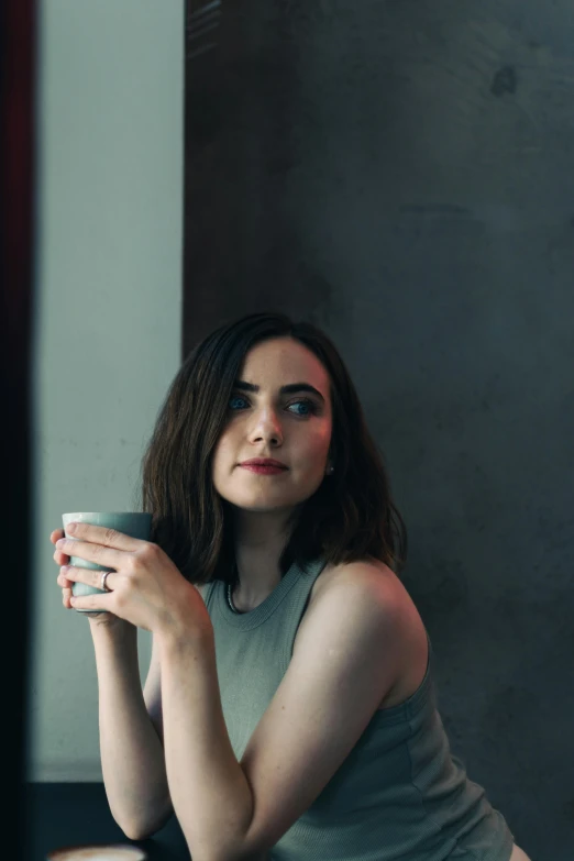 a young woman leaning on a counter drinking a mug