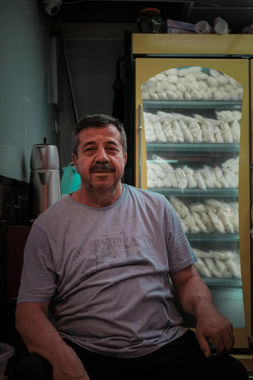 a man sitting in front of a display case full of white cookies