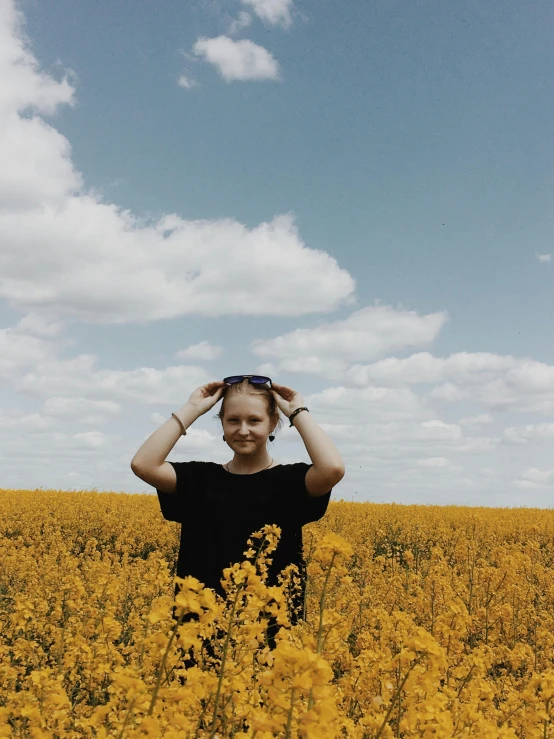 woman in a field of flowers holding her head