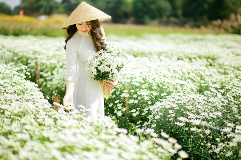 a young woman standing in a field of flowers wearing a hat