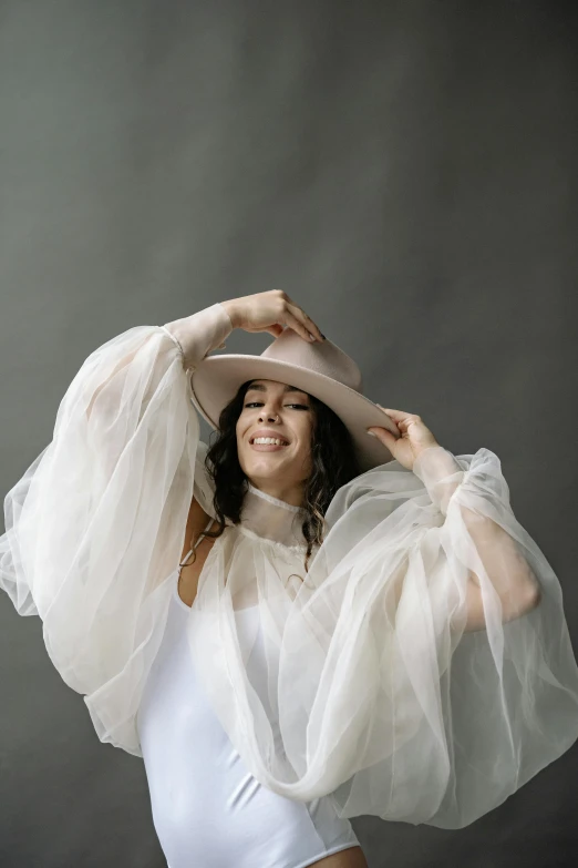 woman in white top and sheer veil on a grey background