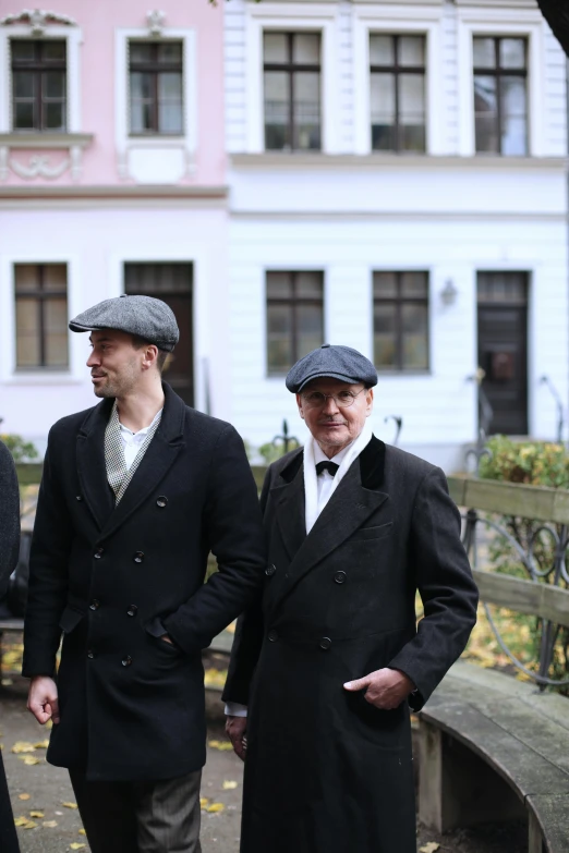 two men with hats standing together in front of a building