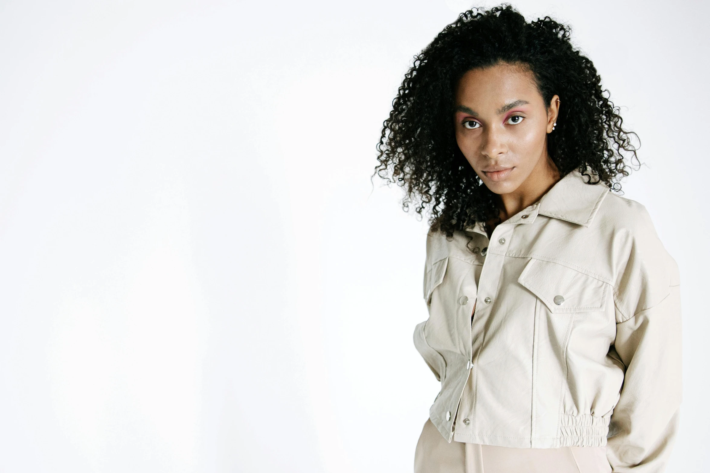 a woman with curly hair in a light jacket