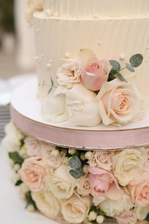 two three tiered wedding cakes with pink and ivory roses