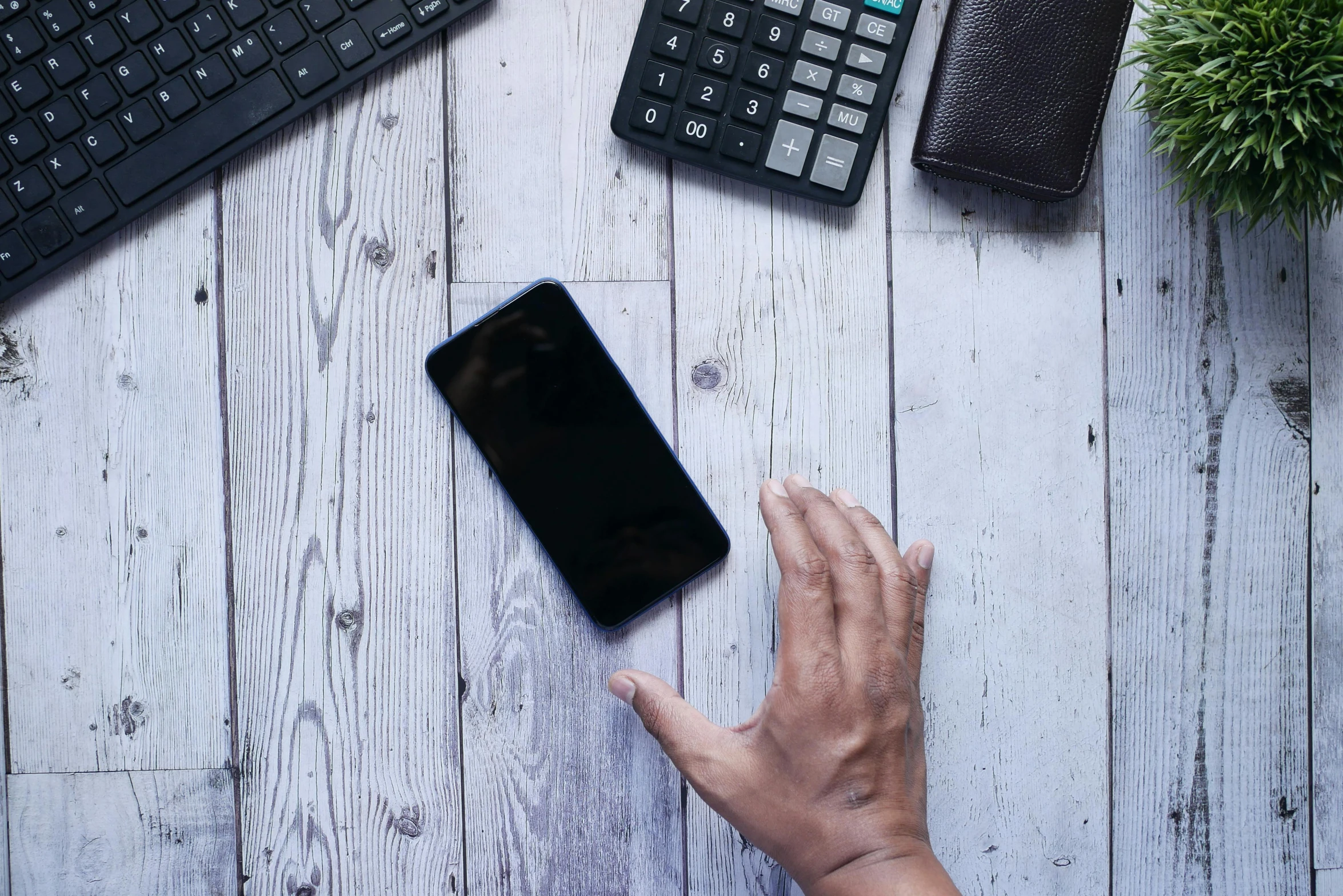 someone using their computer keyboard with a small cellphone