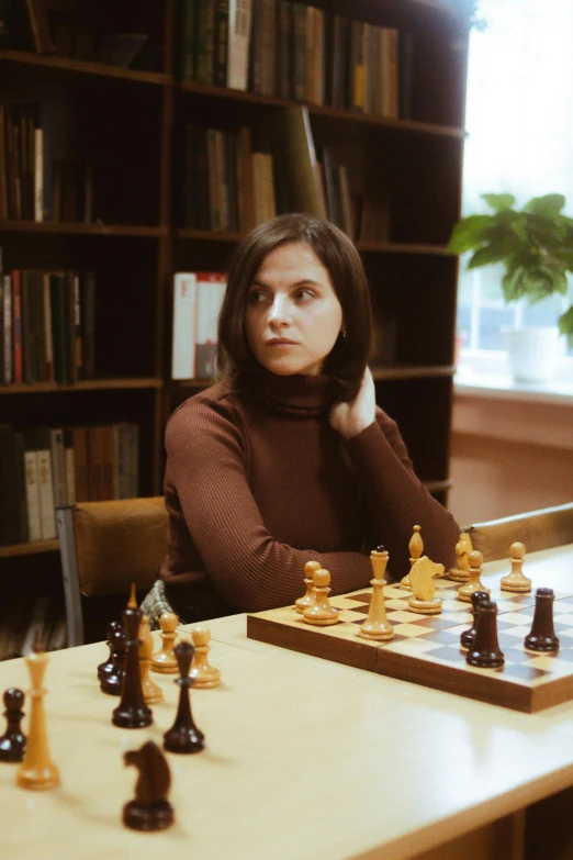 a young lady poses while playing chess in a liry