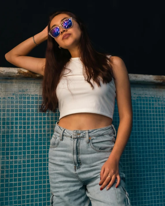 a woman in sunglasses poses by a pool