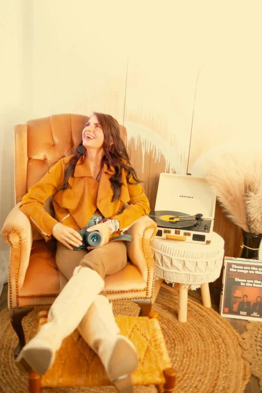 a woman in a yellow coat sits on a chair with a record player and records