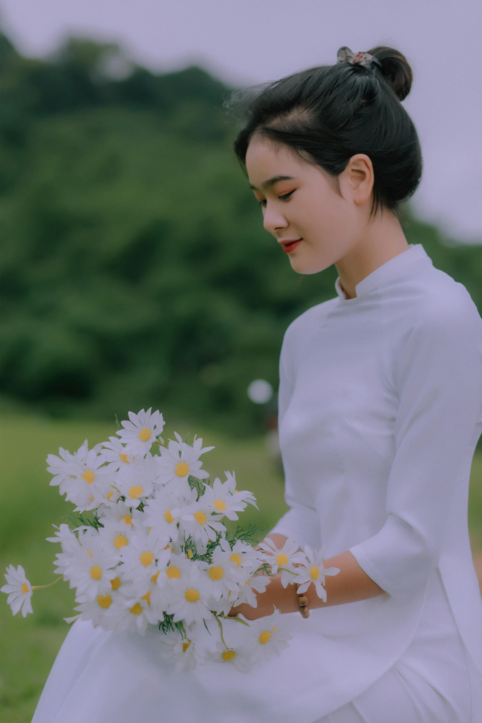 a woman in a white dress holding a bouquet of daisies