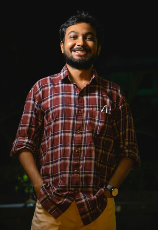 a man wearing a red and yellow plaid shirt smiling