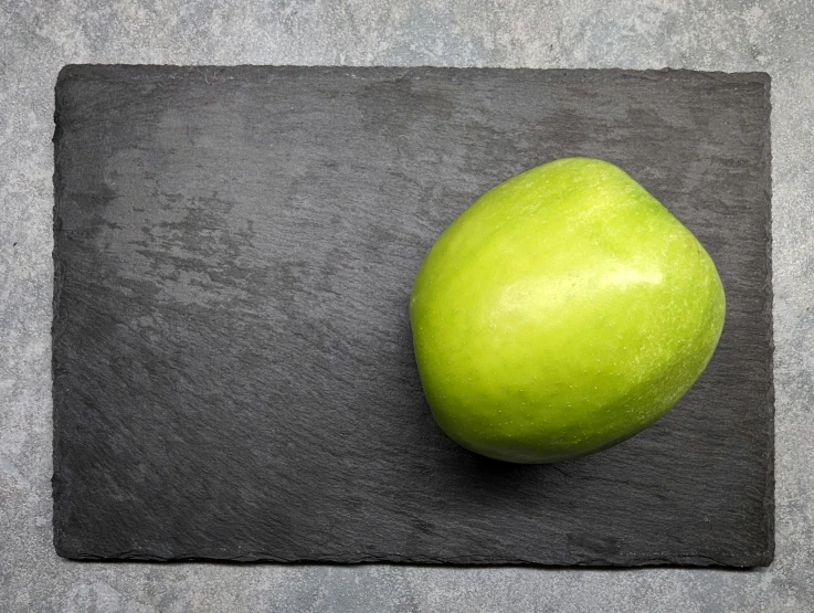 a large apple sits on the surface of a black cloth