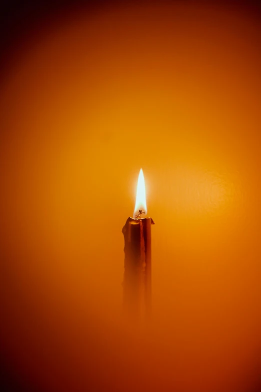 a lit candle in a dark colored environment