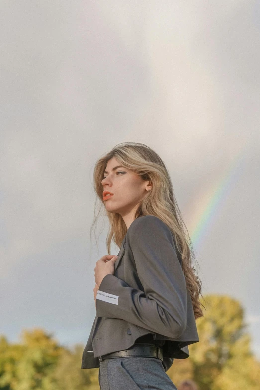 a woman with a long hair standing in front of a rainbow