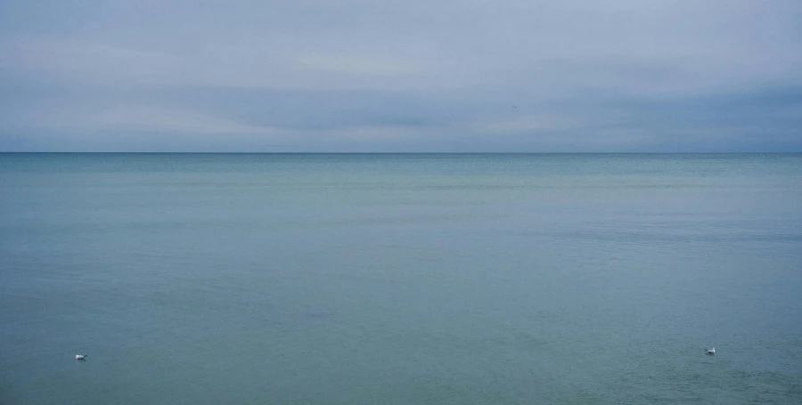 a lone boat on the water with a cloudy sky in the background