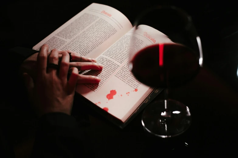 a man reads a book with a glass of wine