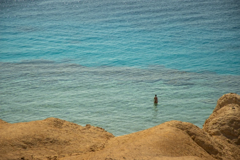 a man in a body of water with surfboard under his arms