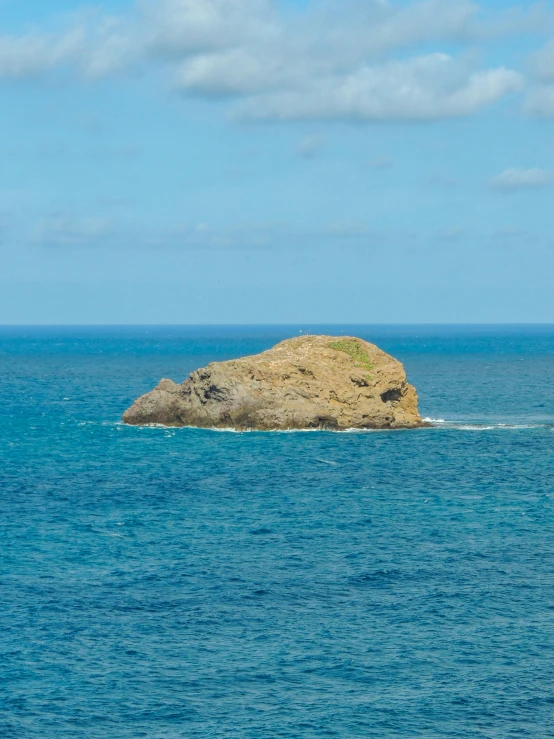 a small island that looks like a stone is in the middle of the ocean